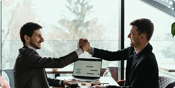 Rectangle 13482 Two business professionals shaking hands in a modern office setting, illustrating website design consultation for aesthetic clinics.